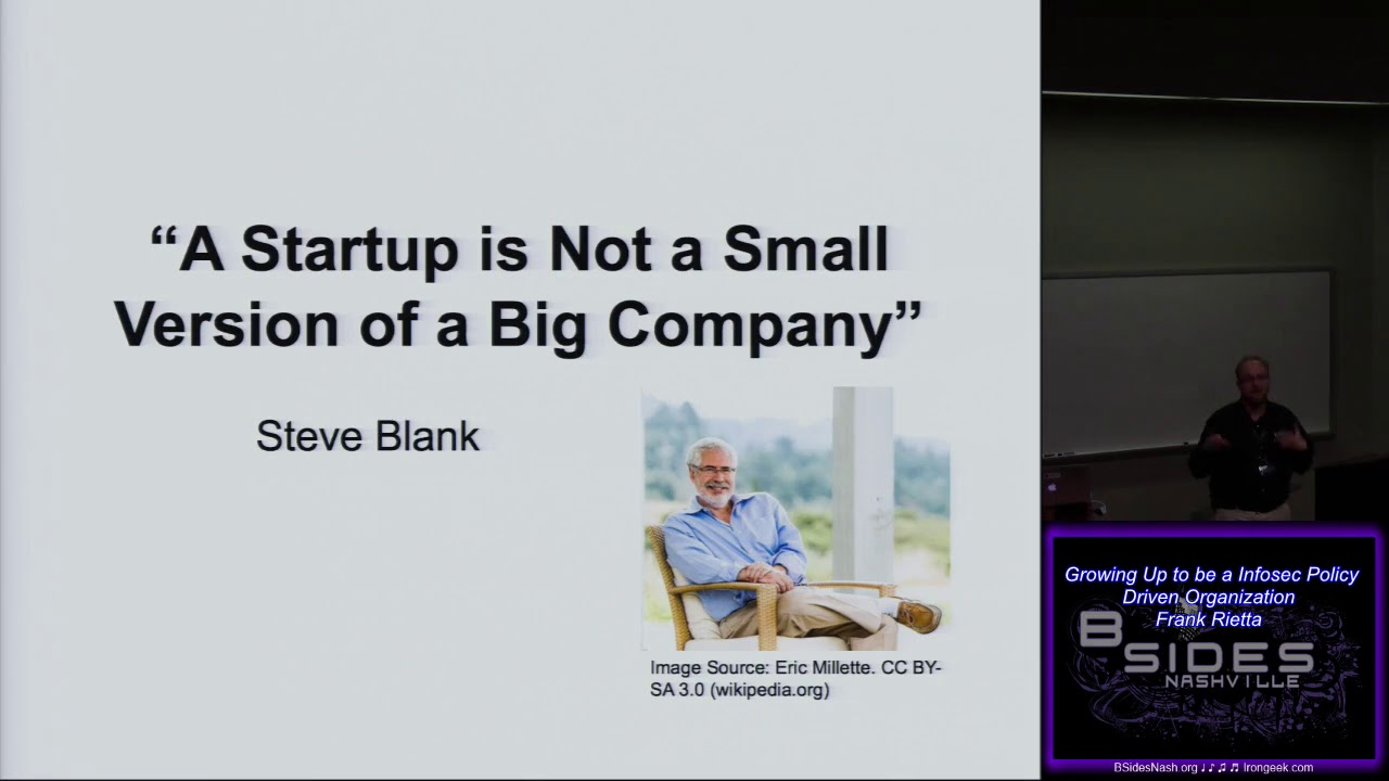Presentation slide quoting Steve Blank, "A Startup is Not a Small Version of a Big Company," with Frank Rietta presenting at BSides Nashville in a corner video window.