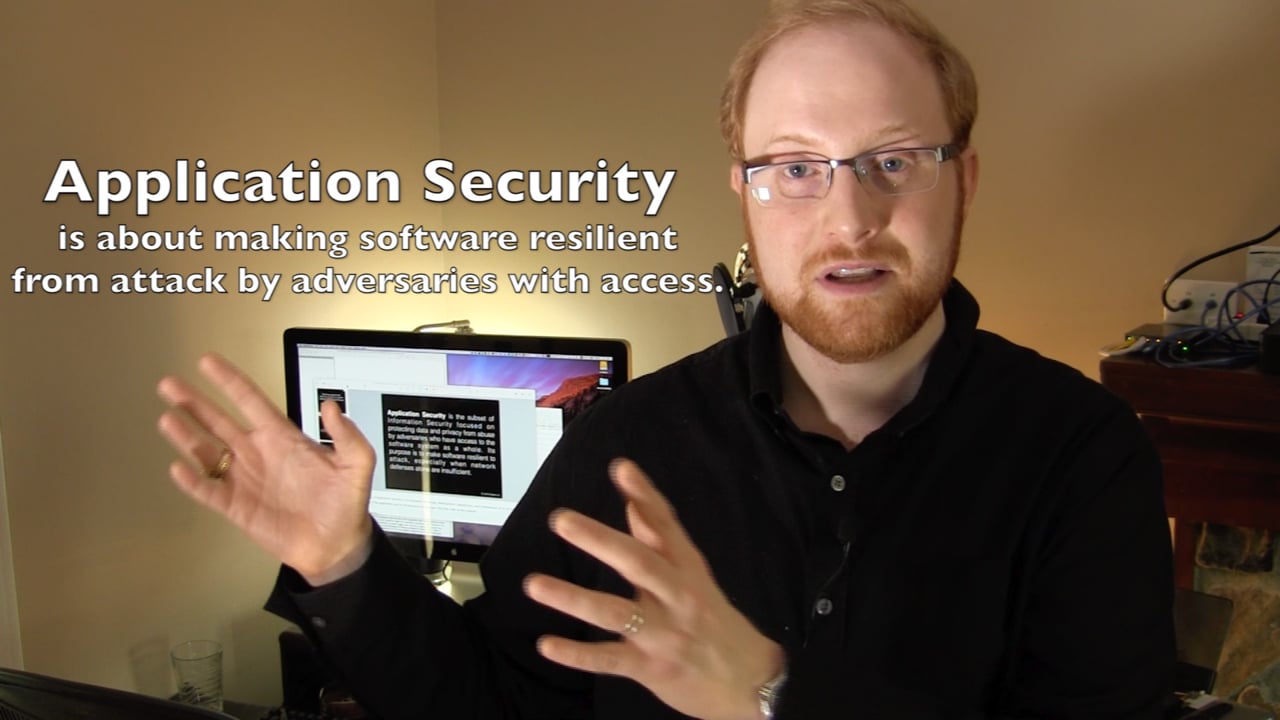 Frank Rietta speaking to camera with a monitor behind him, next to on-screen text reading "Application Security is about making software resilient from attack by adversaries with access."